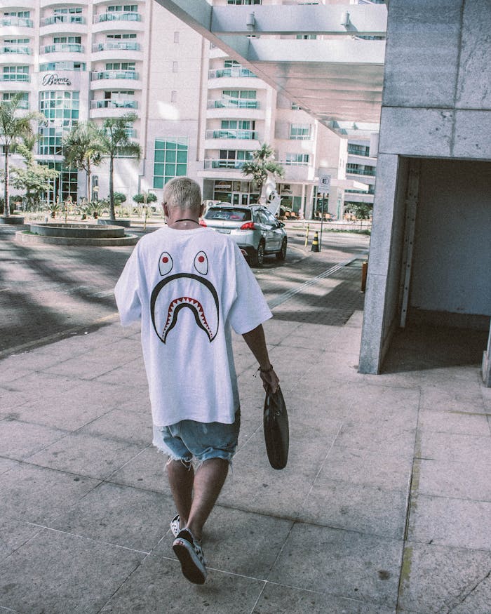 Man in streetwear walking in urban area with buildings in the background.